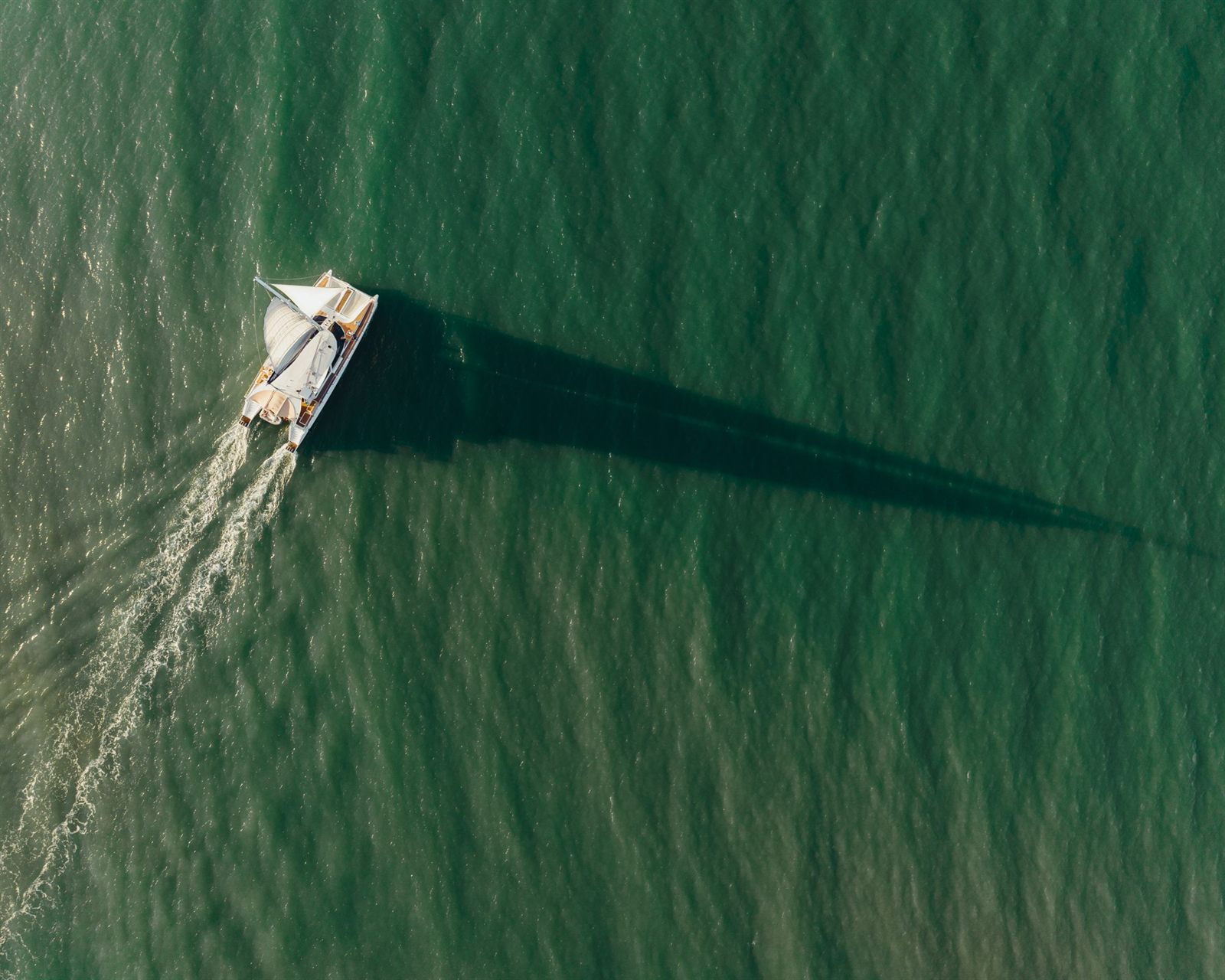 Small boat leaving a white wake across green tropical water
