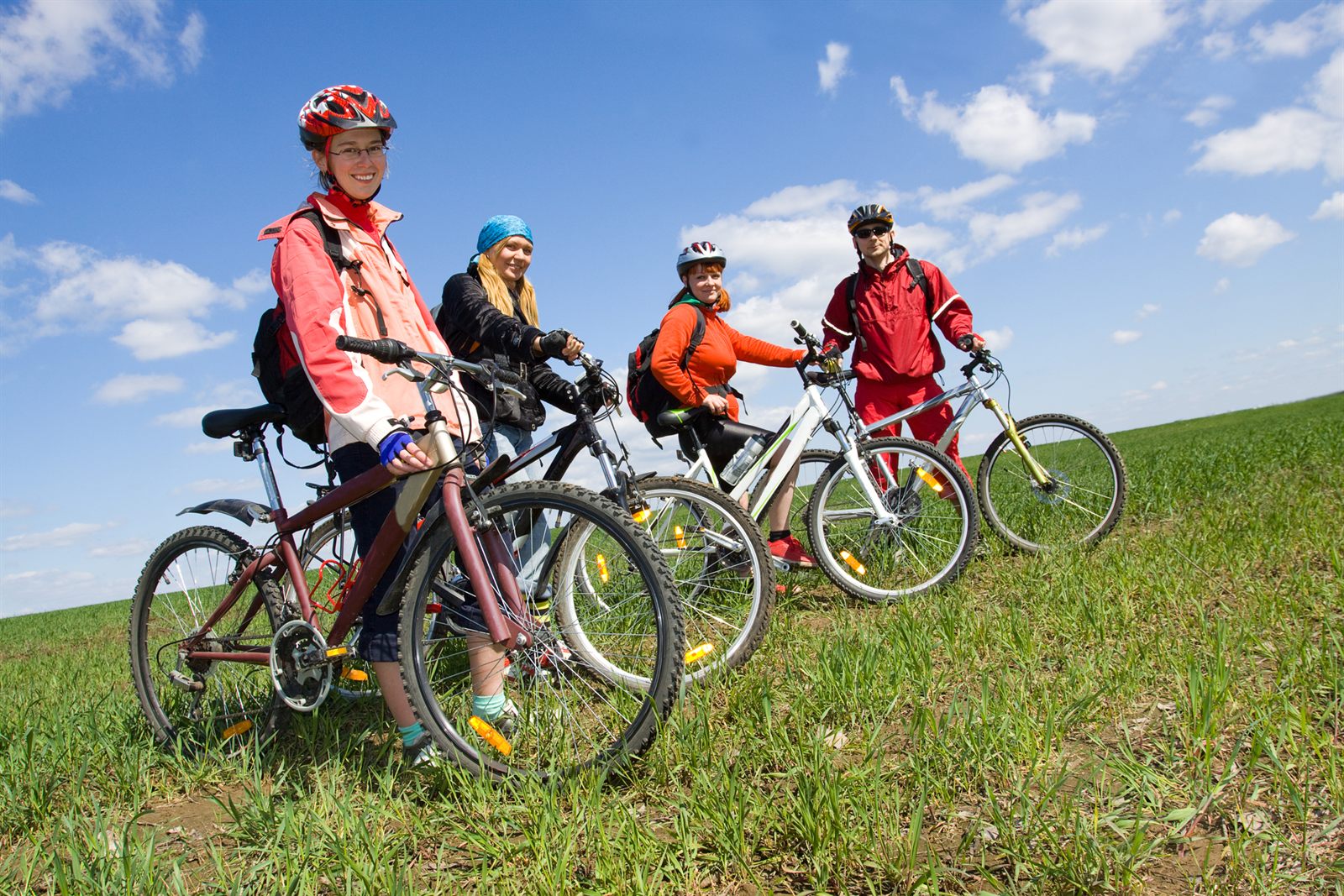 Group of cyclists in helmets on a grassy hilltop