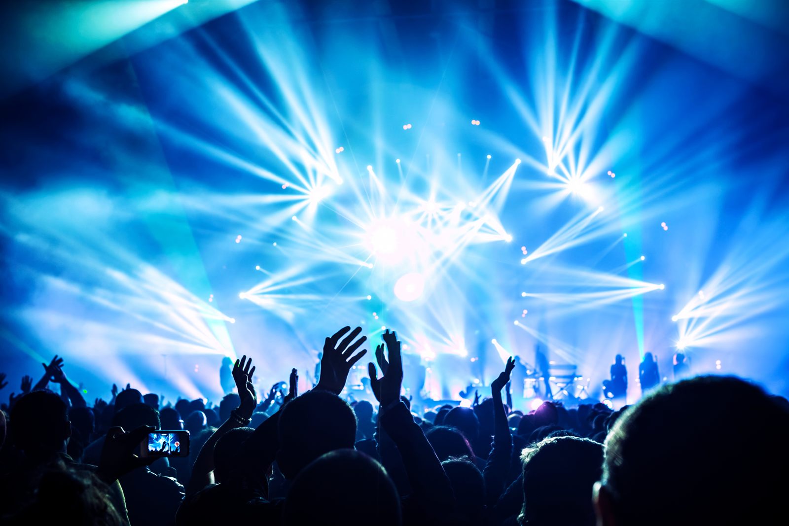 Crowd cheering with arms raised under bright arena lights