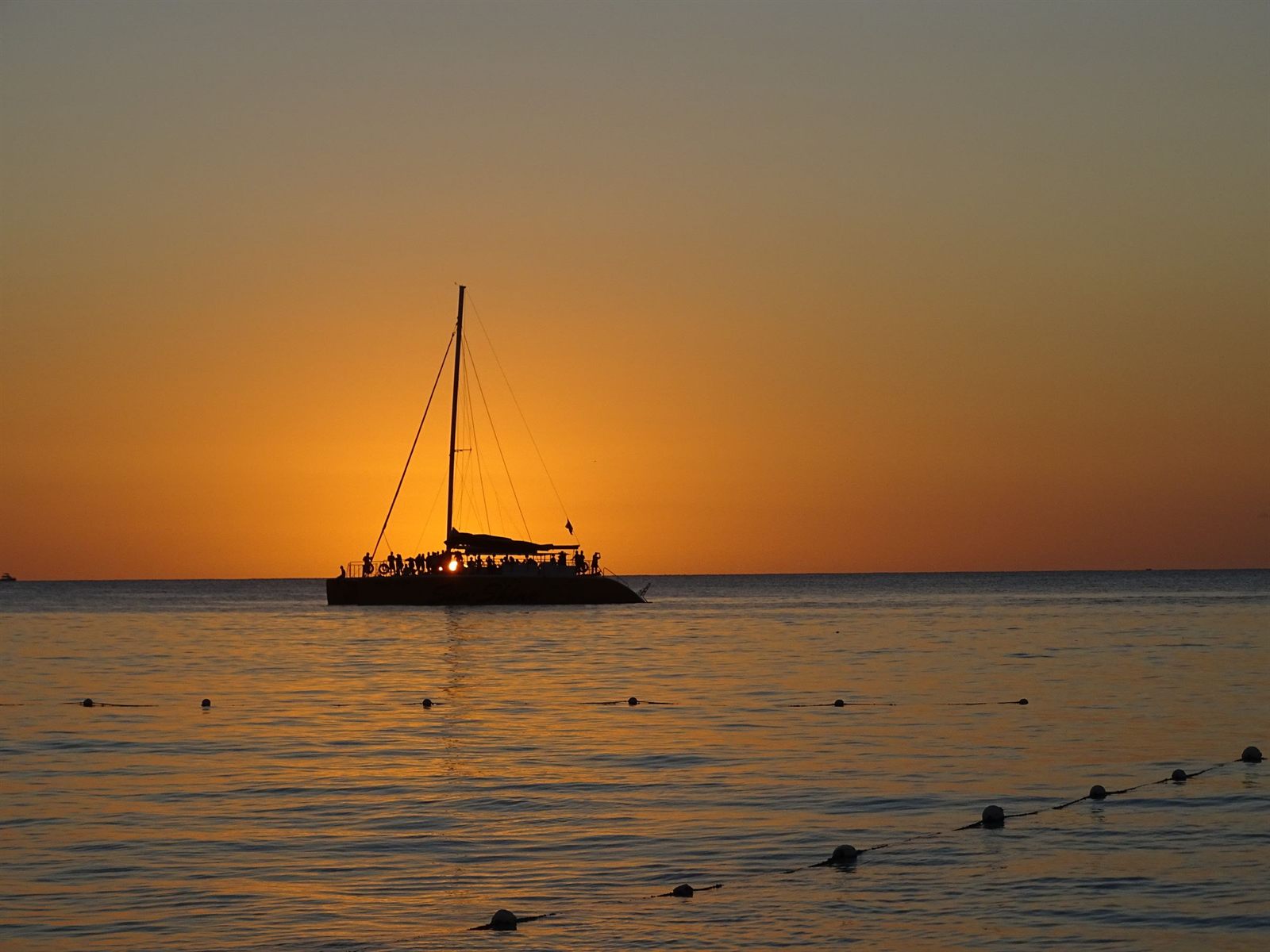 Catamaran silhouetted on calm water at sunset